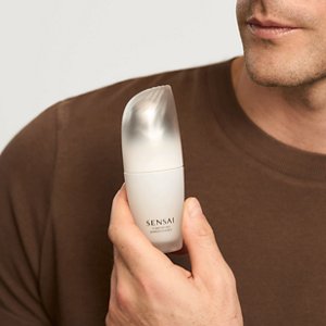 Eine Nahaufnahme des Models, das die Comforting Barrier Essence Flasche in der Hand hält